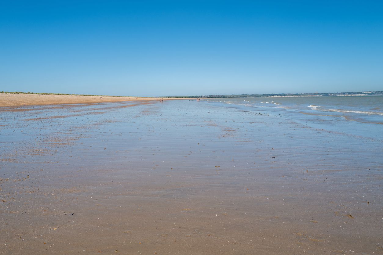 Sandwich, UK - Jan 21 2021 A beautiful shingle and sandy beach on a hot summer day with blue skies. A few people are enjoying the beach which is accessed via a toll gate through a private estate.