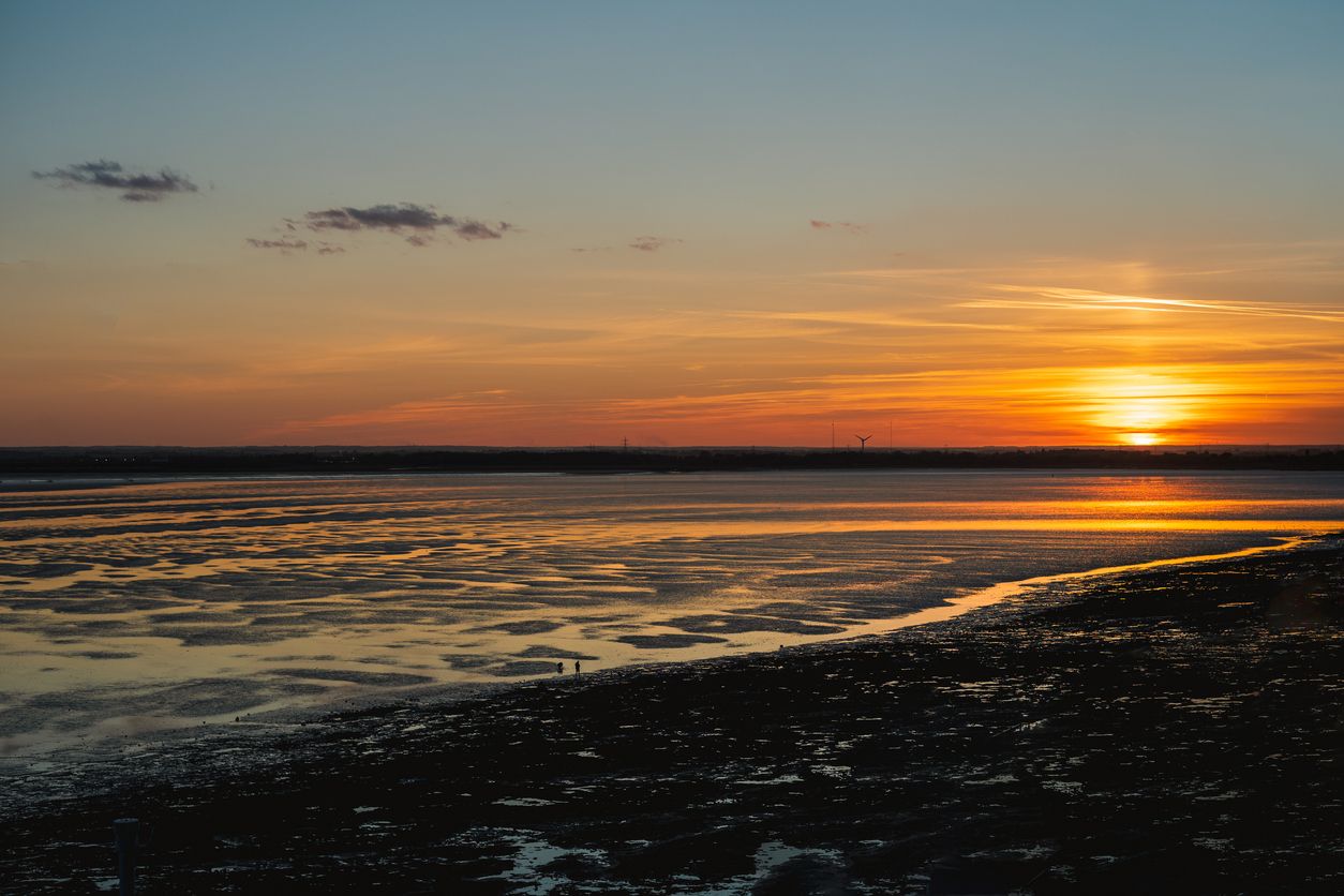 A beautiful sunset at low tide. The sand has a rippled texture and the water is catching the golden light. The view is from Ramsgate looking towards Sandwich, UK